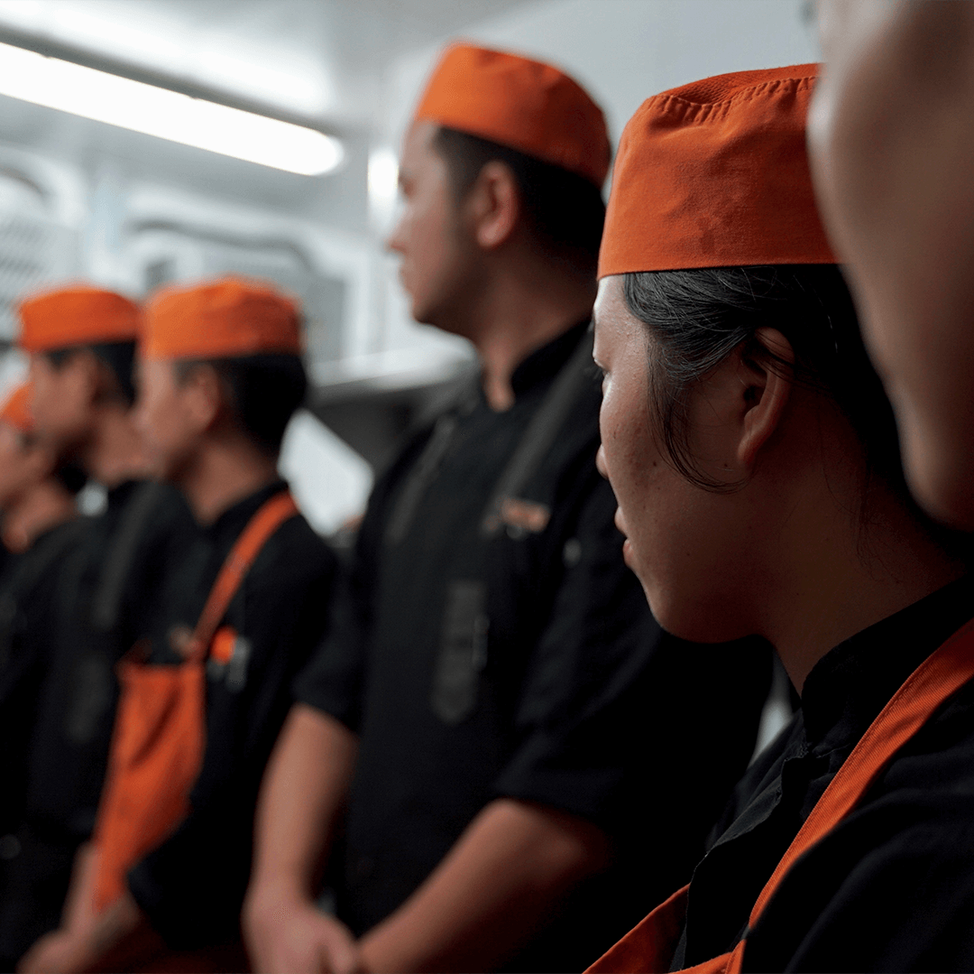 Equipo de cocina reunido con uniforme negro y naranja 