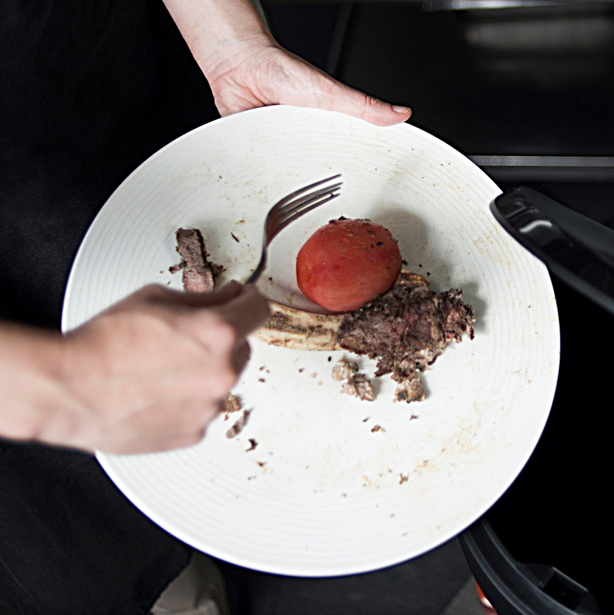 Plato con una chuleta y un tomate para tirar al cubo de basura